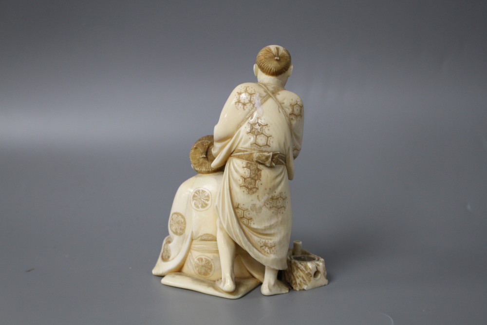A Japanese Meiji period ivory okimono carved with a doctor treating a mans ear, signed, height 12cm